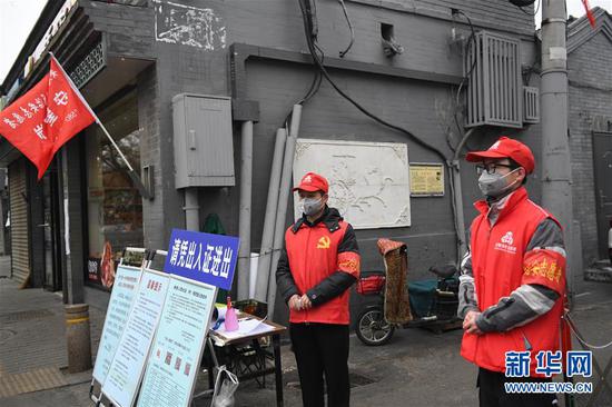 2月27日,志愿者张建国(左)和儿子张洪赫在北京市东城区安定门街道花园社区车辇店胡同口的疫情防控值班点值守。 新华社记者 鞠焕宗 摄