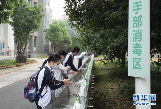 5月6日,武汉首批121所学校高三年级正式复学。在湖北省武昌实验中学,高三年级的学生入校后在手部消毒区洗手。 新华社记者 熊琦 摄